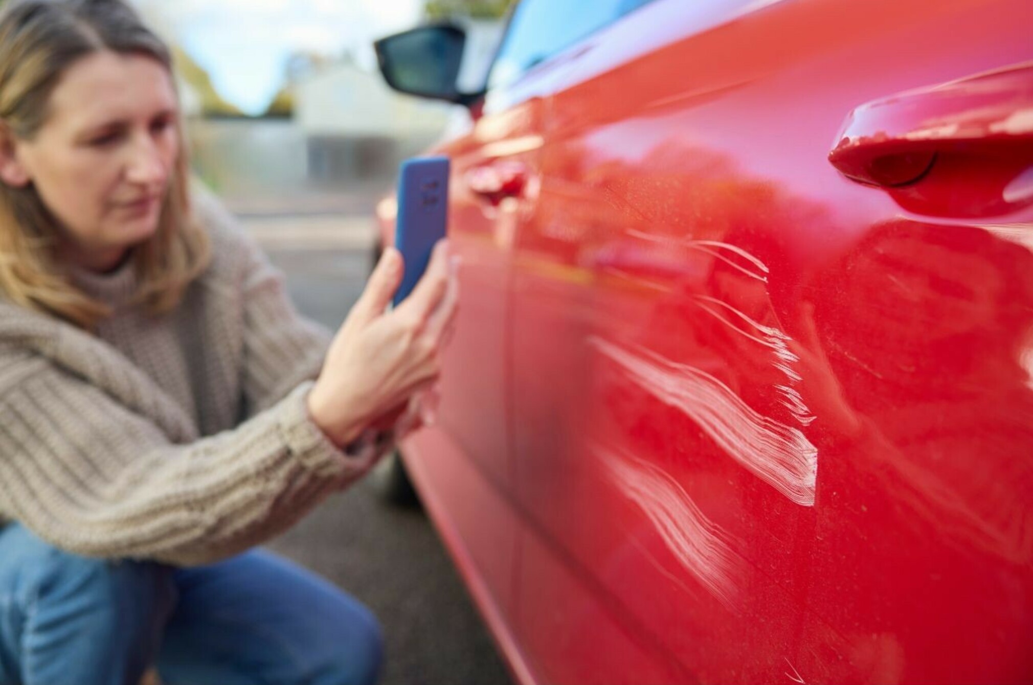 Consumer nz website promo image a woman takes a photo of damage caused to a car for insurance purposes