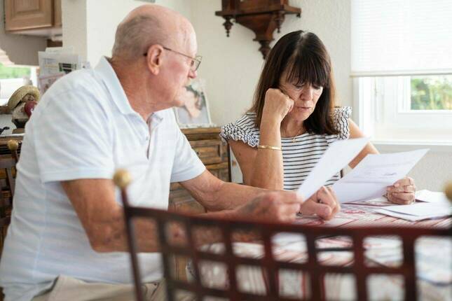 Senior couple sitting at home table managing insurance