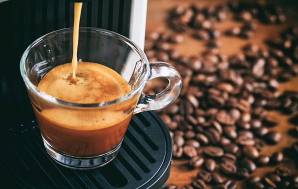 Shot of espresso with coffee beans in background.