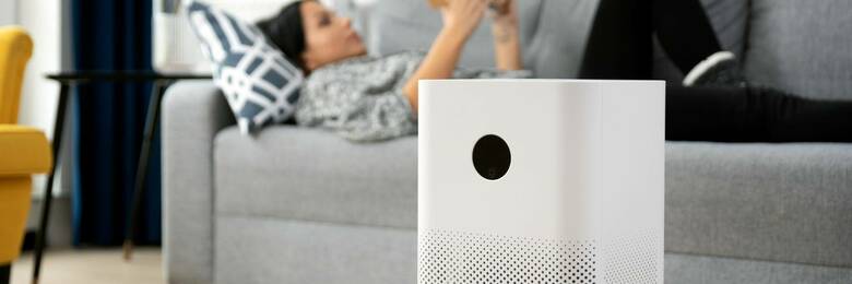 Person using air purifier while reading a book on the couch