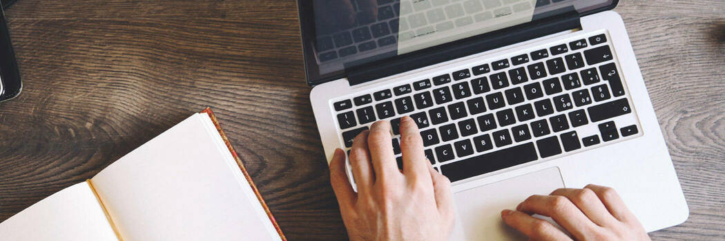 Close-up of person typing on a laptop keyboard.